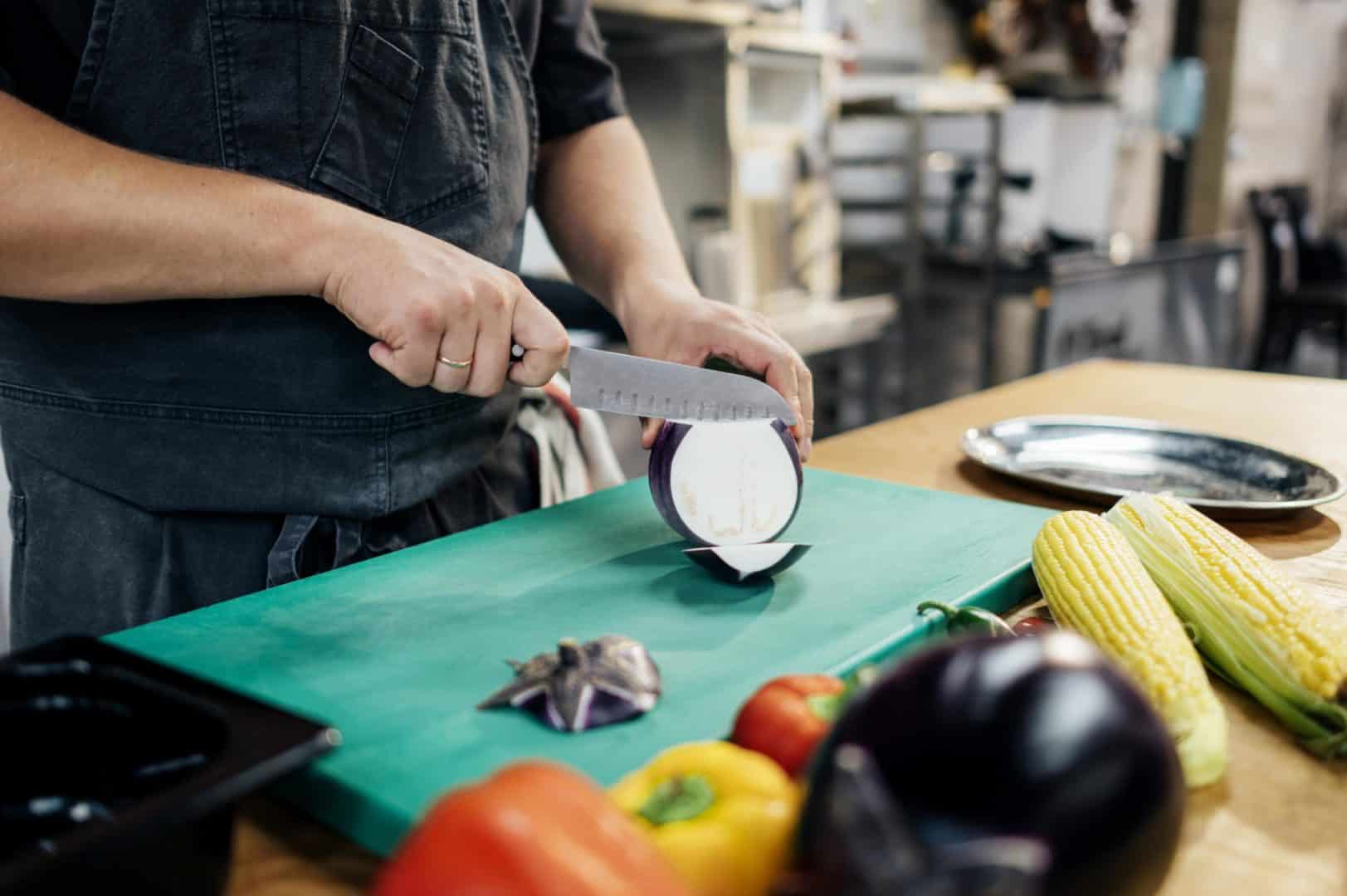 male chef slicing aubergine in the kitchen 1 - CAP
